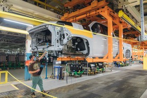 A separated truck cab and bed move through an assembly line at General Motors' Oshawa assembly plant as employees work below