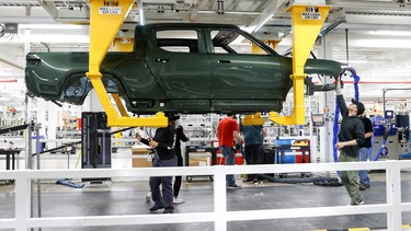 Employees work on an assembly line at startup Rivian Automotive's electric vehicle factory in Normal, Illinois, U.S. April 11, 2022.