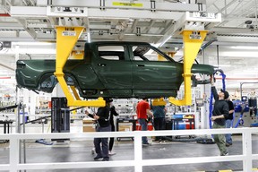 Employees work on an assembly line at startup Rivian Automotive’s electric vehicle factory in Normal, Illinois, U.S. April 11, 2022.