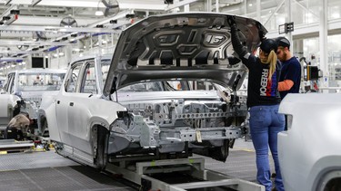 Employees work on an assembly line at startup Rivian Automotive's electric vehicle factory in Normal, Illinois, U.S. April 11, 2022