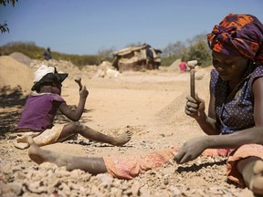 A child and a woman break rocks extracted from a cobalt mine at a copper quarry and cobalt pit in Lubumbashi on May 23, 2016.