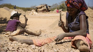 A child and a woman break rocks extracted from a cobalt mine at a copper quarry and cobalt pit in Lubumbashi on May 23, 2016.