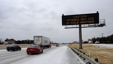 A sign warning about ice on bridges is seen as cars drive on Texas State Highway 183 in the early morning hours on February 1, 2011 in Dallas, Texas.