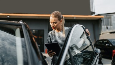 Female used car dealer checking vehicle before customer