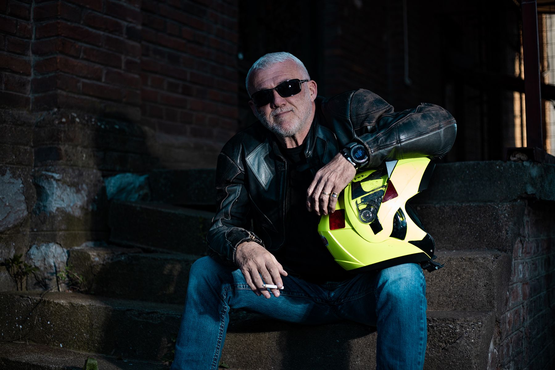 An older man holding a motorcycle helmet