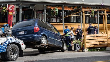 A mini-van is removed from a patio outside Bottlescrew Bill's Pub in Calgary's Beltline on Thursday.
