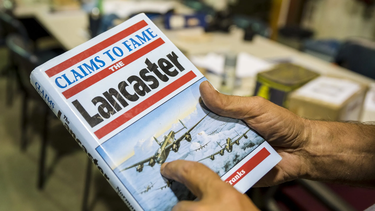 National Air Force Museum of Canada Restoration Technician Mike Joly holds a book that details the history of the iconic Avro Lancaster aircraft. The team uses historical resources like the book to maintain an accurate restoration of the aircraft.