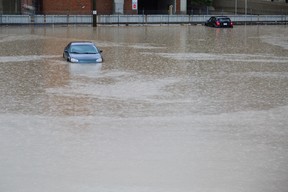 Two abandoned cars lie partially submerged after floodwaters fill the parking lot