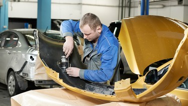 A collision-repair technician working on a car's bumper