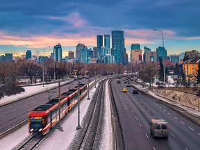 A view of cars and a city train commuting towards downtown Calgary in the winter