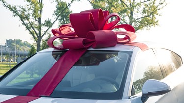 New car gift. New white car with red gift ribbon.