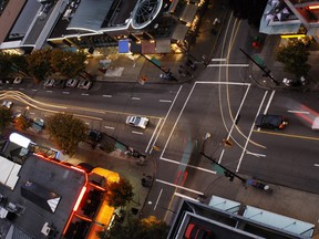 One of Vancouver's intersections in a shopping district at dusk, seen from above, with cars changing lanes, waiting for the traffic lights to turn green, accelerating, swerving and maneuvering