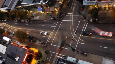 One of Vancouver's intersections in a shopping district at dusk, seen from above, with cars changing lanes, waiting for the traffic lights to turn green, accelerating, swerving and maneuvering