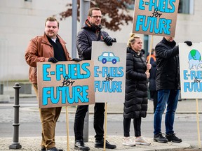 People display placards promoting so-called e-fuels on the sidelines of a mobility summit at the Chancellery in Berlin on January 10, 2023