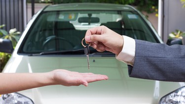 A woman buying a car is handed the keys by the seller