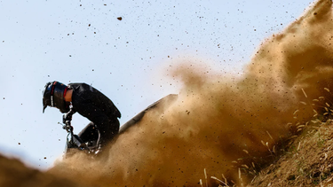 A rider on a Ducati motorcycle kicking up dirt