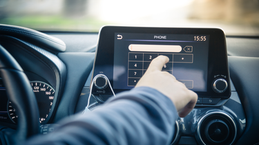 The driver of a car places a phone call via the infotainment screen