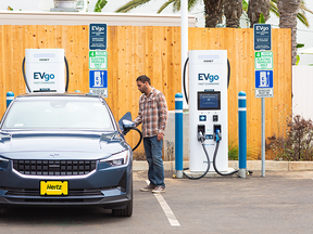 A customer charges a Hertz vehicle at an EVGo charger