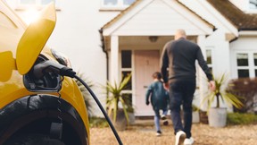 Electric car charging on driveway outside house