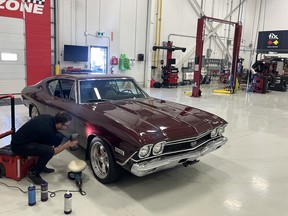 A Fix Auto technician looks at damage on the fender of Mike Hall's 1968 Chevrolet Chevelle