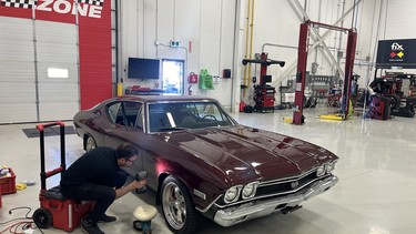 A Fix Auto technician looks at damage on the fender of Mike Hall's 1968 Chevrolet Chevelle