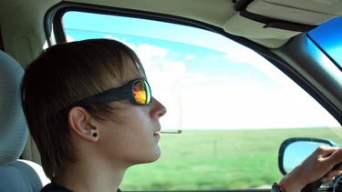 A teenage boy smoking a marijuana joint while driving