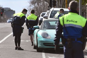 Police officers pull a car over for a licence and permit check in Melbourne on August 11, 2020, during a strict stage four lockdown of the city due to a COVID-19 coronavirus outbreak