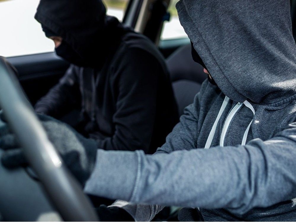 A pair of car thieves inside a stolen vehicle in this stock image.