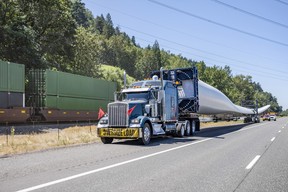 A large truck with an 'Oversize Load' sign transporting an electric-generator windmill blade