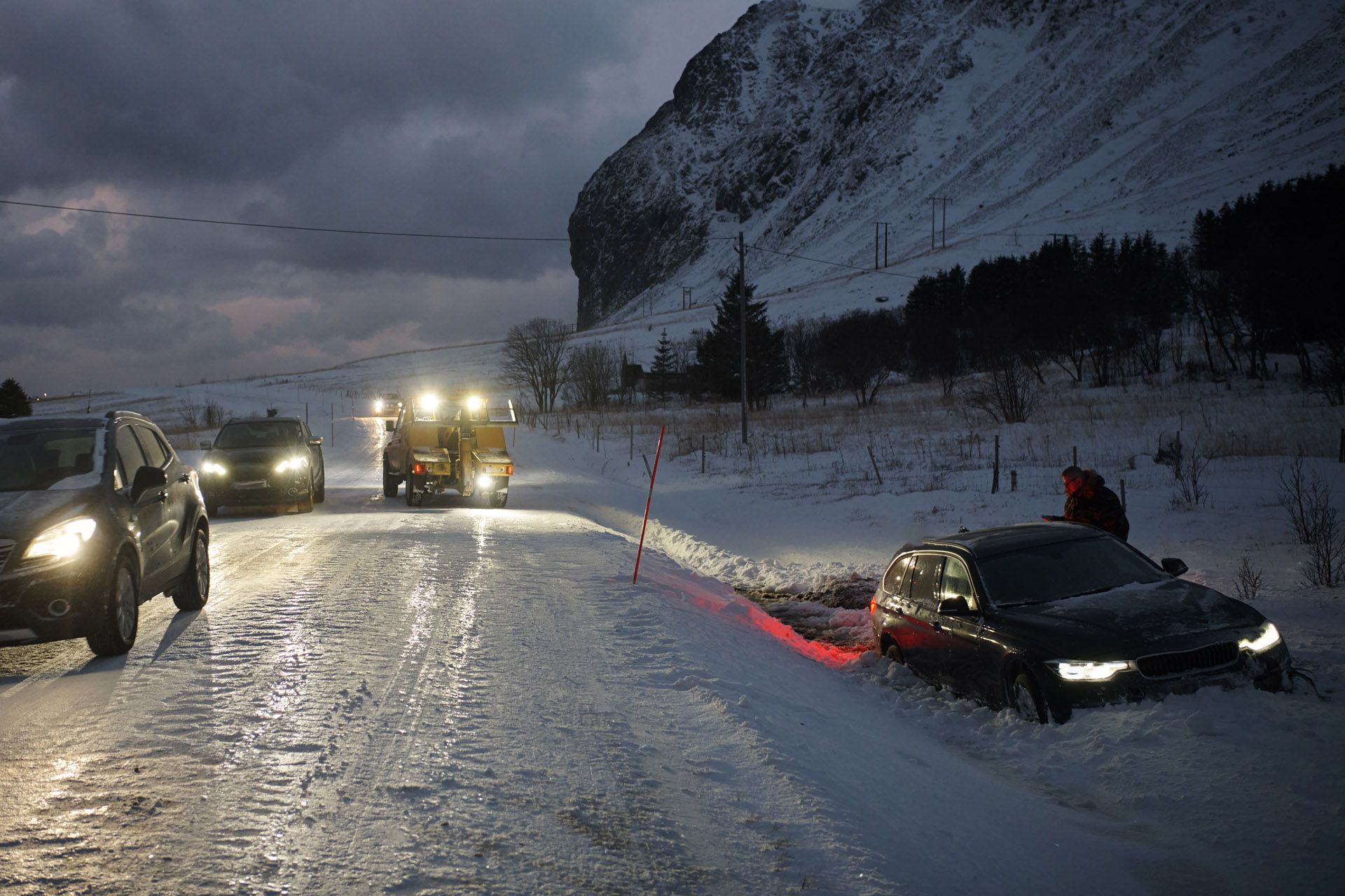A car being towed after an accident in a snow-storm on an icy Scandinavian road at night