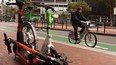 A cyclist rides an e-bike by electric scooters parked on Market Street on July 29, 2024 in San Francisco, California