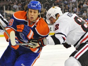 EDMONTON, AB. FEBRUARY 9, 2011 -Ryan Jones (28) of the Edmonton Oilers chases a loose puck into the corner but is held up by Duncan Keith of the Chicago Blackhawks at Rexall Place in Edmonton. (SHAUGHN BUTTS/EDMONTON JOURNAL)
