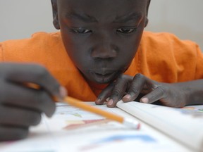 Eight-year old Sudanese-Canadian William Monga concentrates during a Saturday morning homework club. Photo by Shaughn Butts / Edmonton Journal