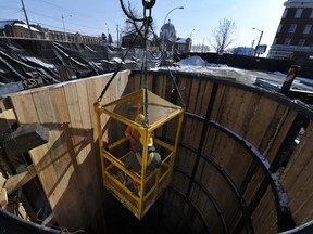 City workers Ryan Thompson and Lucien Gayagay get lifted out of a hole for a mole tunnel bore for the new stormwater pipe at Jasper Ave and 96 Street on March 1, 2012. Photo by John Lucas/Edmonton Journal