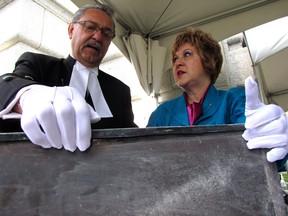 Speaker Gene Zwozdesky and Culture Minister Heather Klimchuk inspect the 1909 time capsule moments after it was pulled from behind the cornerstone of Alberta's Legislature on June 18, 2012.