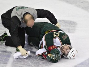 Minnesota Wild forward Cal Clutterbuck is tended to by a trainer after being hit by Edmonton Oilers forward Taylor Hall during the visiting Wild's 3-1 win at Rexall Place Feb. 21, 2013. Photo by Jason Franson/The Canadian Press