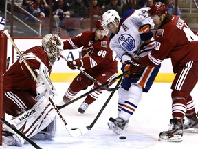 Edmonton Oilers forward Jordan Eberle (14) tries to move the puck in front of Phoenix Coyotes goalie Chad Johnson, left, as Coyotes' Alex Bolduc (49) and Mikkel Boedker (89) defend Jan. 30, 2013, in Glendale, Ariz. Photo by /Ross D. Franklin/Associated Press