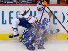 Edmonton Oilers' Eric Belanger, top, and Vancouver Canucks' Aaron Volpatti collide during the second period of an NHL hockey game in Vancouver, B.C., on Sunday January 20, 2013. THE CANADIAN PRESS/Darryl Dyck