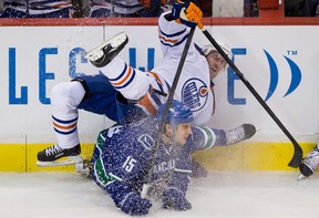 Edmonton Oilers' Eric Belanger, top, and Vancouver Canucks' Aaron Volpatti collide during the second period of an NHL hockey game in Vancouver, B.C., on Sunday January 20, 2013. THE CANADIAN PRESS/Darryl Dyck