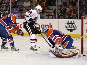 Patrick Kane slips the puck behind Devan Dubnyk moments after slipping his entire body behind Justin Schultz and the other Oilers skaters.  (Photo by Perry Nelson/Getty Images)