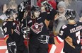 Gregory Chase (centre) celebrates a goal for the Calgary Hitmen. (Photo credit: Calgary Herald)