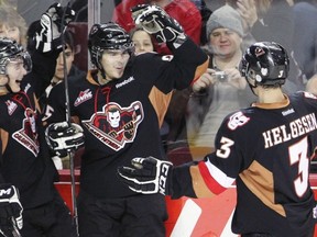 Gregory Chase (centre) celebrates a goal for the Calgary Hitmen. (Photo credit: Calgary Herald)