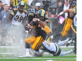 Hamilton Tiger-Cats’ Lindsey Lamar, front, is tackled by Edmonton Eskimos’ Calvin McCarthy, top, and Grant Shaw during first half CFL action in Guelph, Ont., on Sunday, July 7, 2013.
Photograph by: Aaron Lynett, THE CANADIAN PRESS