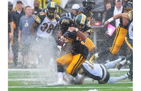 Hamilton Tiger-Cats’ Lindsey Lamar, front, is tackled by Edmonton Eskimos’ Calvin McCarthy, top, and Grant Shaw during first half CFL action in Guelph, Ont., on Sunday, July 7, 2013.
Photograph by: Aaron Lynett, THE CANADIAN PRESS