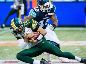 Edmonton Eskimos quarterback Mike Reilly, front, avoids a tackle from Toronto Argonauts linebacker Robert McCune, back, during first half CFL action in Toronto, on Sunday, August 18, 2013.
Photograph by: Nathan Denette, The Canadian Press.
