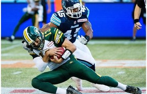 Edmonton Eskimos quarterback Mike Reilly, front, avoids a tackle from Toronto Argonauts linebacker Robert McCune, back, during first half CFL action in Toronto, on Sunday, August 18, 2013.
Photograph by: Nathan Denette, The Canadian Press.