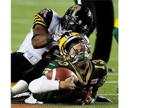 Edmonton Eskimos’ Mike Reilly #13 has his helmet pulled up by Hamilton Tiger-Cats’ Nate Bussey #6 during second-half action on August 2, 2013, at Commonwealth Stadium in Edmonton.
Photograph by: Greg Southam, Edmonton Journal