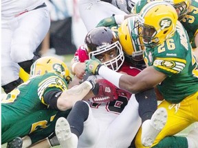 Calgary Stampeders’ Marquay McDaniel, centre, is tackled by Edmonton Eskimos’ Mike Miller, left, and Donovan Richard, centre right, during first half Canadian Football League game action in Edmonton on Friday Sept. 6, 2013.
Photograph by: JASON FRANSON, THE CANADIAN PRESS