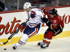 Edmonton Oilers' defenceman Philip Larsen, left, grabs the puck away from Calgary Flames forward Mike Cammalleri during first period NHL pre-season hockey action in Calgary, Alta., Saturday, Sept. 14, 2013.