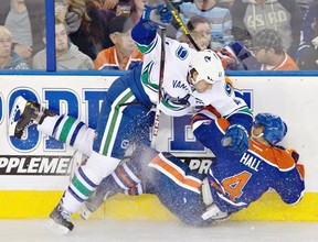 Vancouver Canucks' Andrew Alberts, 41, checks Edmonton Oilers Taylor Hall, 4, during first period pre-season NHL hockey action in Edmonton, Alta., on Saturday September 21, 2013. THE CANADIAN PRESS/Jason Franson